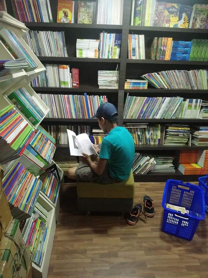 Photo of author sitting and reading a book in a bookstore